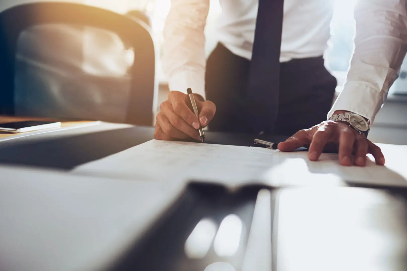 A man in a suit and tie writing on paper.