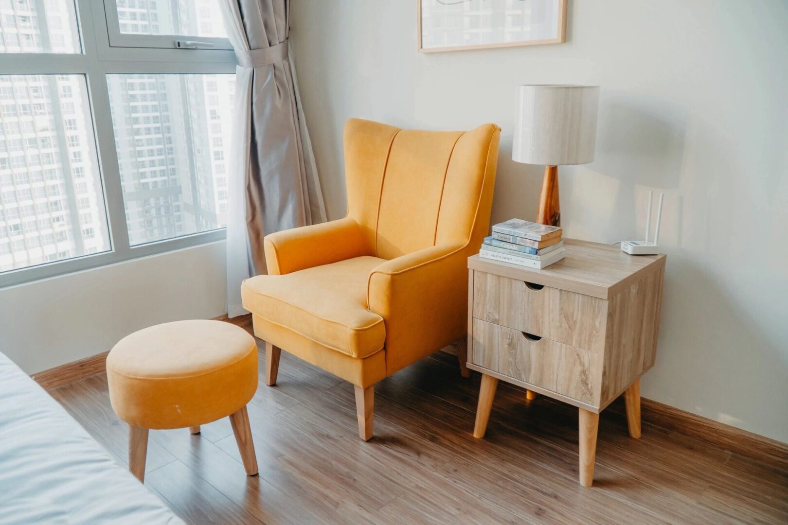 A yellow chair and ottoman in front of a window.